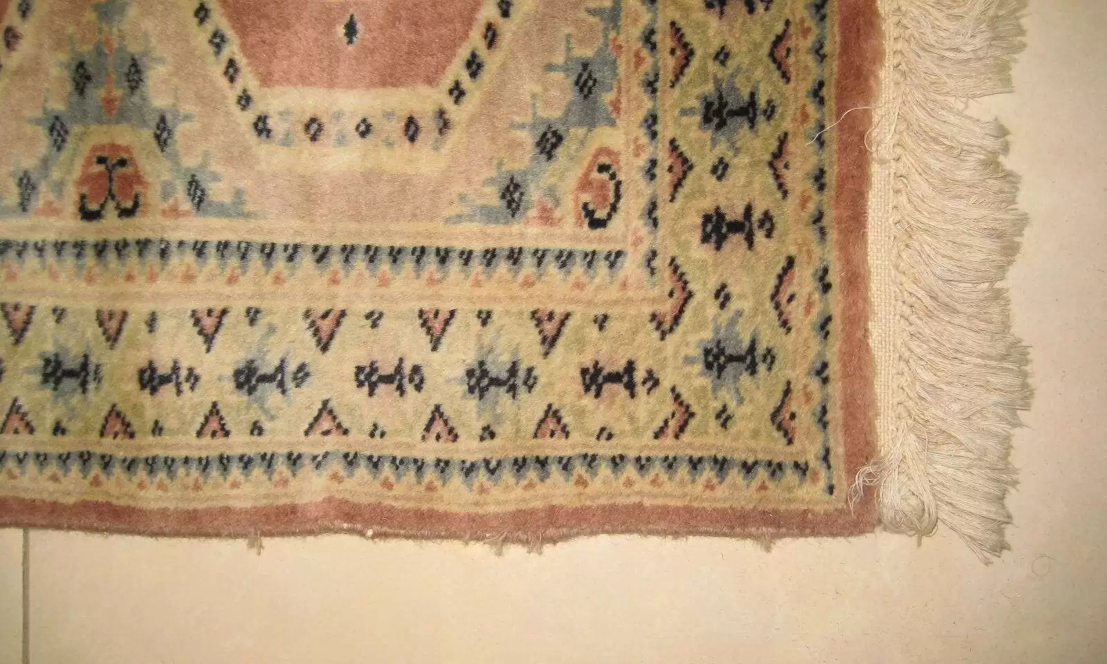 Gros plan sur un tapis montrant la zone restaurée d'une déchirure, désormais invisible