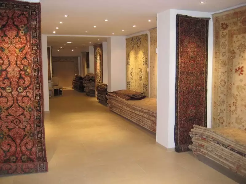 Intérieur chaleureux du magasin Mastour Gallery avec des tapis exposés.