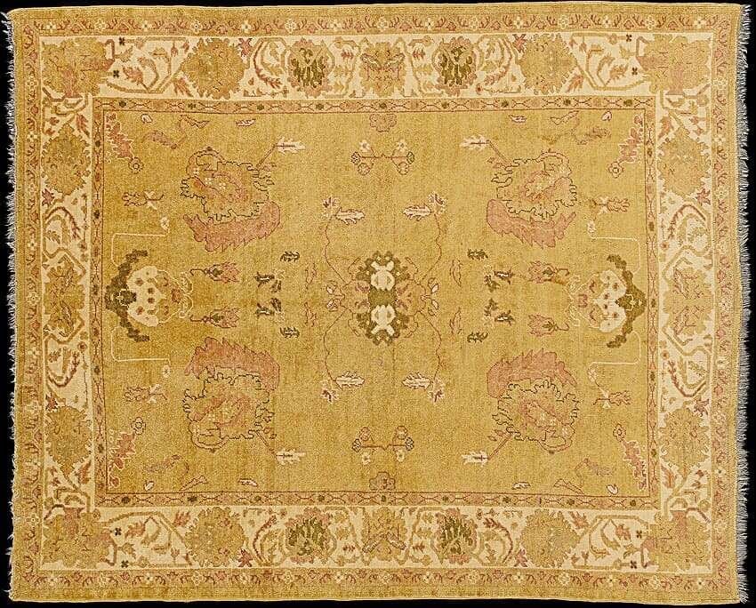 Tapis turc vintage tissé à la main avec des motifs floraux complexes dans des tons de jaune clair et de rose pâle, mettant en valeur l'artisanat traditionnel.