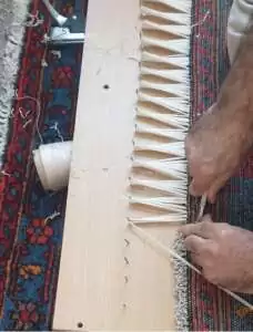 Réparateur professionnel restaurant les franges d'un tapis ancien.