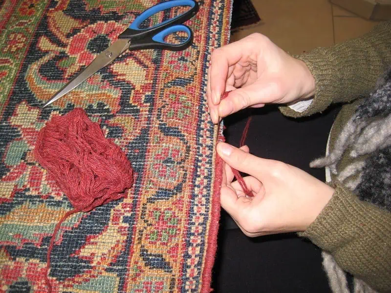 Mains d'experte réparant un tapis d'Orient ancien- Bruxelles/Mastour Gallery