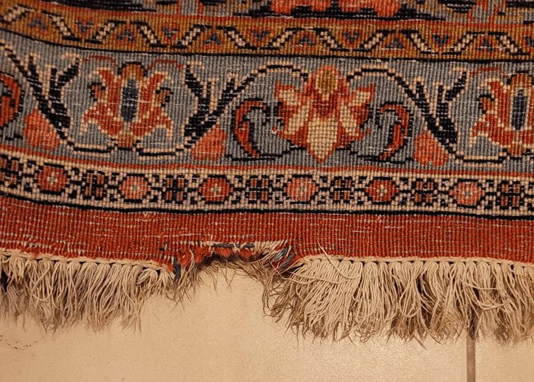 réparation tapis persan Tapis persan ancien avec un trou visible avant réparation