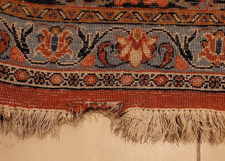 Tapis persan ancien avec un trou visible avant réparation