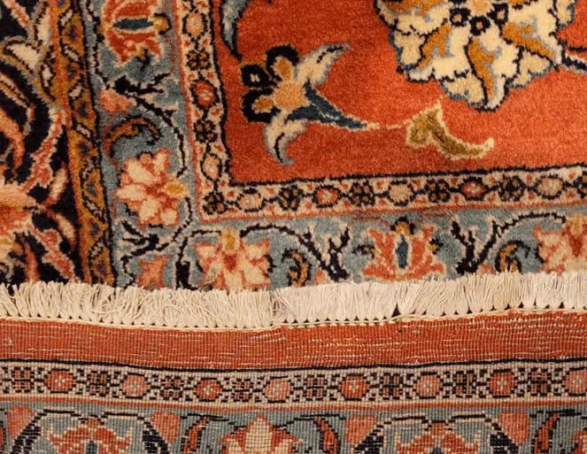 Tapis persan avec trou professionnellement réparé, montrant le résultat final.