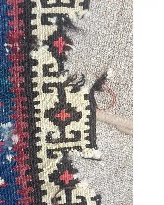 Gros plan sur un trou endommagé dans un kilim turc ancien, nécessitant une réparation