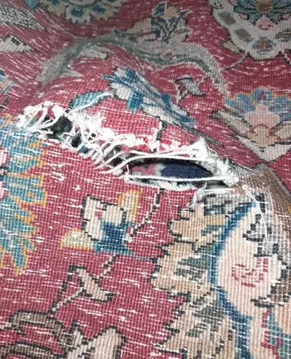 Déchirure importante sur un tapis oriental avant réparation par un professionnel